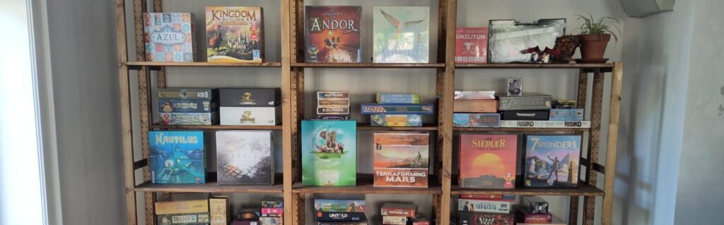 Das mit Brettspielen gefüllte Holzregal der Alea Spielbar